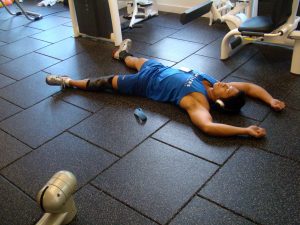 Man lying down on the gym floor tired
