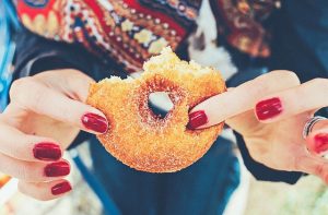 woman's fingers holding half-eaten donut